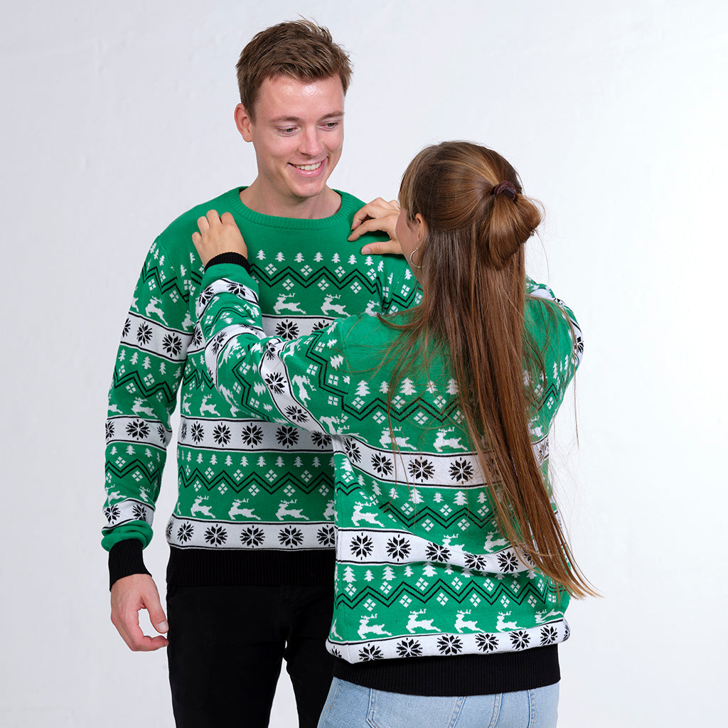 Ett par i grön jultröja med renar och julmönster.